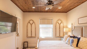 A bedroom with a bed, a ceiling fan, a window with blinds, and a wall-mounted TV. - Getaway by Silver Sands Vacation Rentals (Port Aransas)