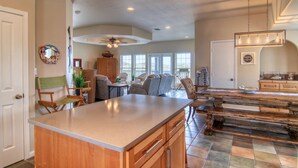 A spacious kitchen with a large island, wooden cabinets, and a dining area with chairs and a table. - Happy Heron by Silver Sands Vacation Rentals (Port Aransas)