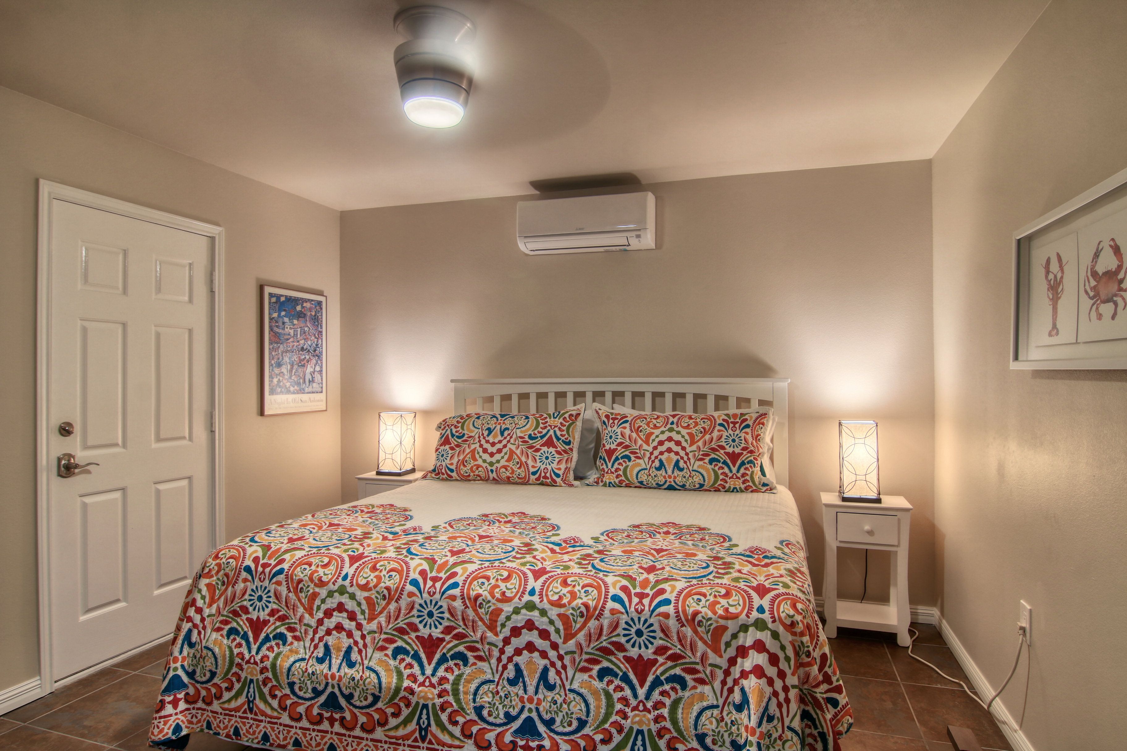 Une chambre à coucher avec un grand lit, deux tables de chevet, un appareil de climatisation et une porte.