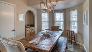 A dining area with a wooden table, chairs, and a hanging light fixture. - Happy Heron by Silver Sands Vacation Rentals (Port Aransas)