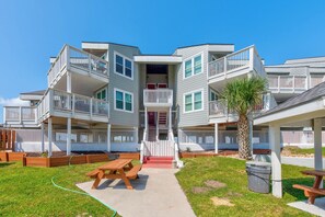 A multi-story residential building with balconies, a central staircase, and a small outdoor seating area. - Gulf Breeze by Silver Sands Vacation Rentals (Port Aransas)