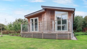 A modern wooden cabin with a balcony, large windows, and a grassy yard. - 2 Meadow Retreat (Liskeard)