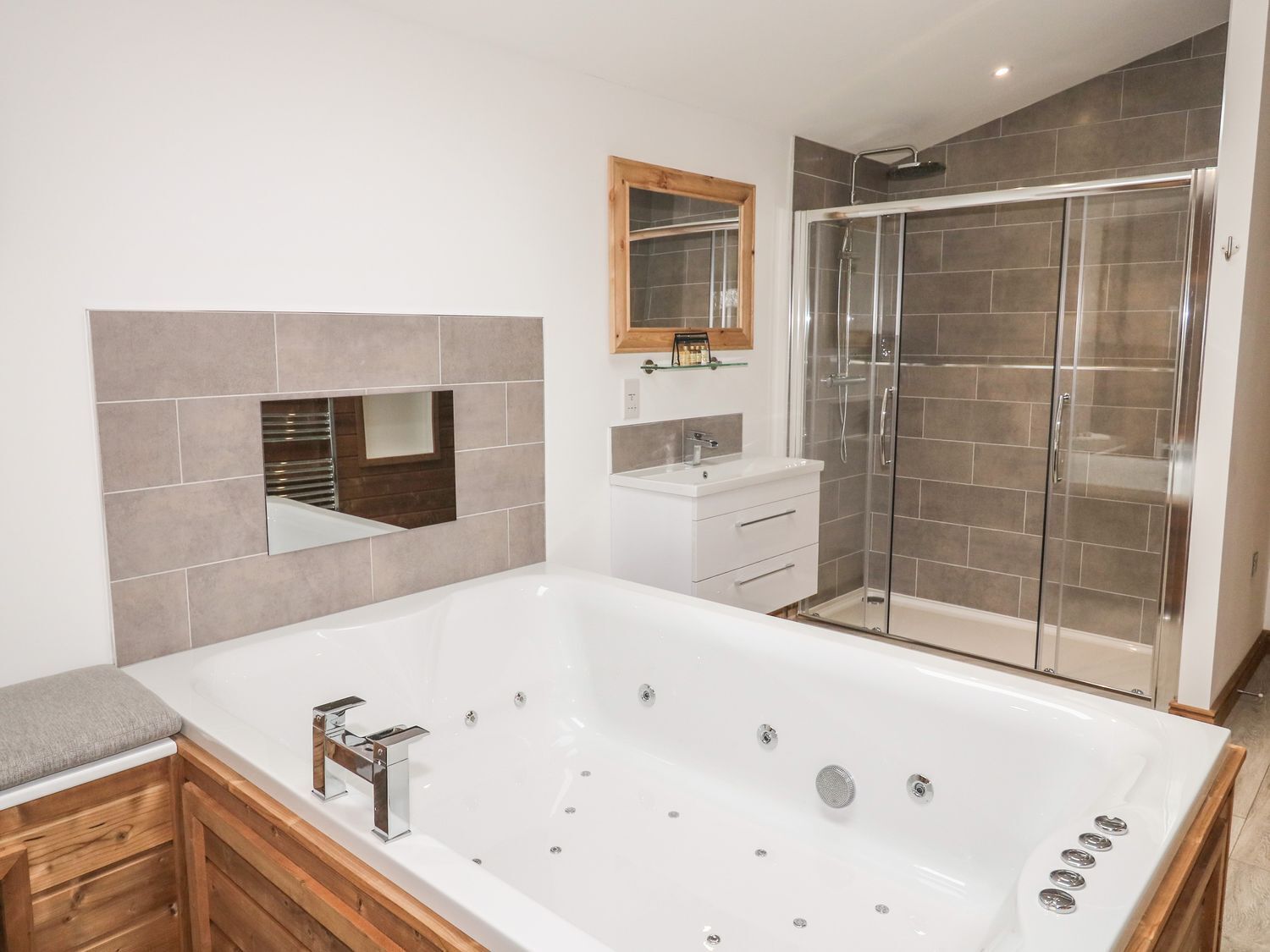 A modern bathroom with a large bathtub, a glass shower enclosure, and a wooden vanity.
