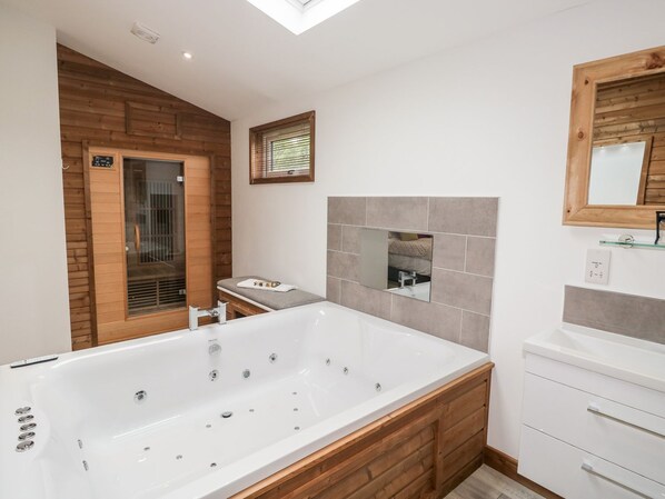 Un baño moderno con una bañera grande, un tocador de madera y un espejo.