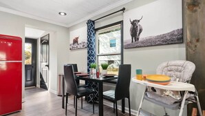 A modern kitchen with a red refrigerator, a dining table with chairs, and a high chair. - Sharpe Tiny House — Cozy, Remodeled Home with Big Amenities (Statesville)