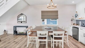 Une cuisine moderne avec un coin repas, un plancher en bois et un lustre.
