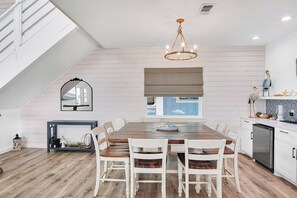 A modern kitchen with a dining area, wooden flooring, and a chandelier. - Holy Moly by Silver Sands Vacation Rentals (Port Aransas)