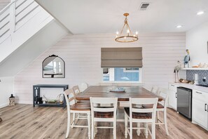 A modern kitchen with a dining area, wooden flooring, and a chandelier. - Holy Moly by Silver Sands Vacation Rentals (Port Aransas)