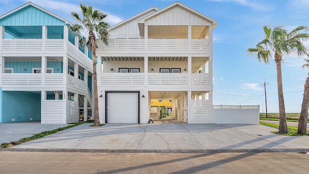 Une maison à deux étages située en bord de mer, dotée d’un porche avant couvert, d’un garage et d’une cour arrière clôturée.