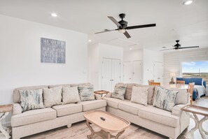 A living room with a beige sectional sofa, a wooden coffee table, and a ceiling fan. - Holy Moly by Silver Sands Vacation Rentals (Port Aransas)