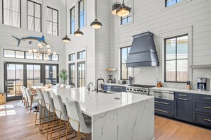 A modern kitchen with a large island, bar stools, and a built-in stove. - Hooty And The Blowfish by Silver Sands Vacation Rentals (Port Aransas)