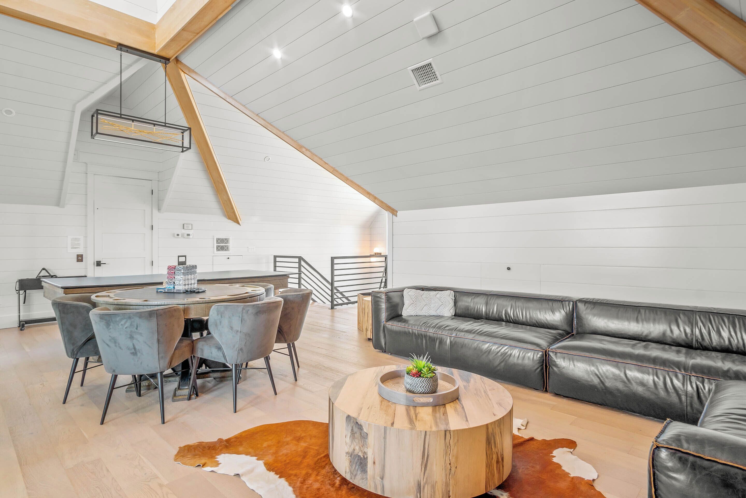 A modern loft-style living space with a dining area, a leather sofa, and a wooden coffee table.