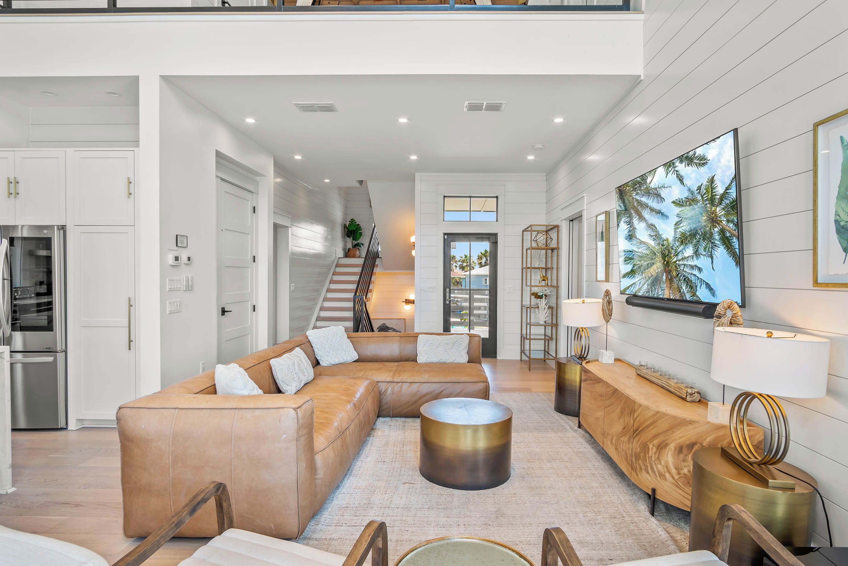 A modern living room with a sectional sofa, a round coffee table, and a staircase leading to an upper level.