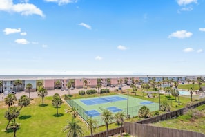 Ein Hotel mit Tennisplatz, Pool und Blick auf den Strand.
