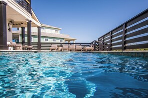 A swimming pool with lounge chairs and a building with a balcony in the background. - Hooty And The Blowfish by Silver Sands Vacation Rentals (Port Aransas)