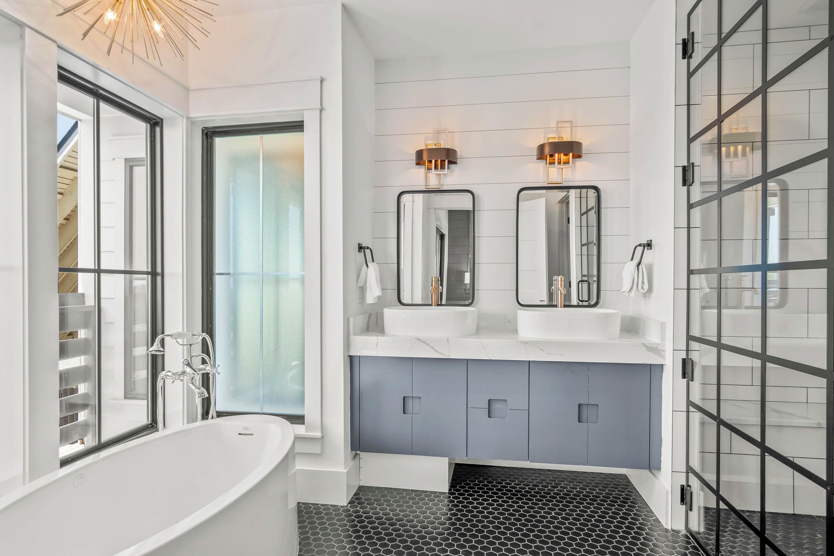 A modern bathroom with a freestanding bathtub, dual sinks, and a glass shower enclosure.