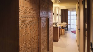 A hotel room with a large wooden partition, a desk, a chair, a lamp, and a large window with curtains. - Safari Hotel Beekse Bergen (Hilvarenbeek)