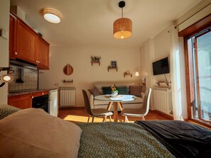 A compact living space with a kitchenette, dining area, and a bed.