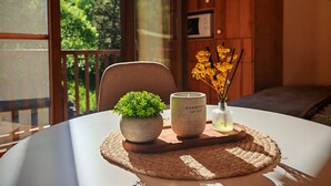 Une table ronde agrémentée d’un set de table en fibres tressées, d’une plante en pot, d’une bougie Harmony et d’un diffuseur à bâtonnets.