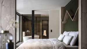 Een moderne slaapkamer met een groot bed, een douchecabine van glas en uitzicht op de omgeving.