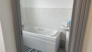 A bathroom with a bathtub, a sink, and a shower. - Cosy Stay In Birmingham by Villazu (Birmingham)