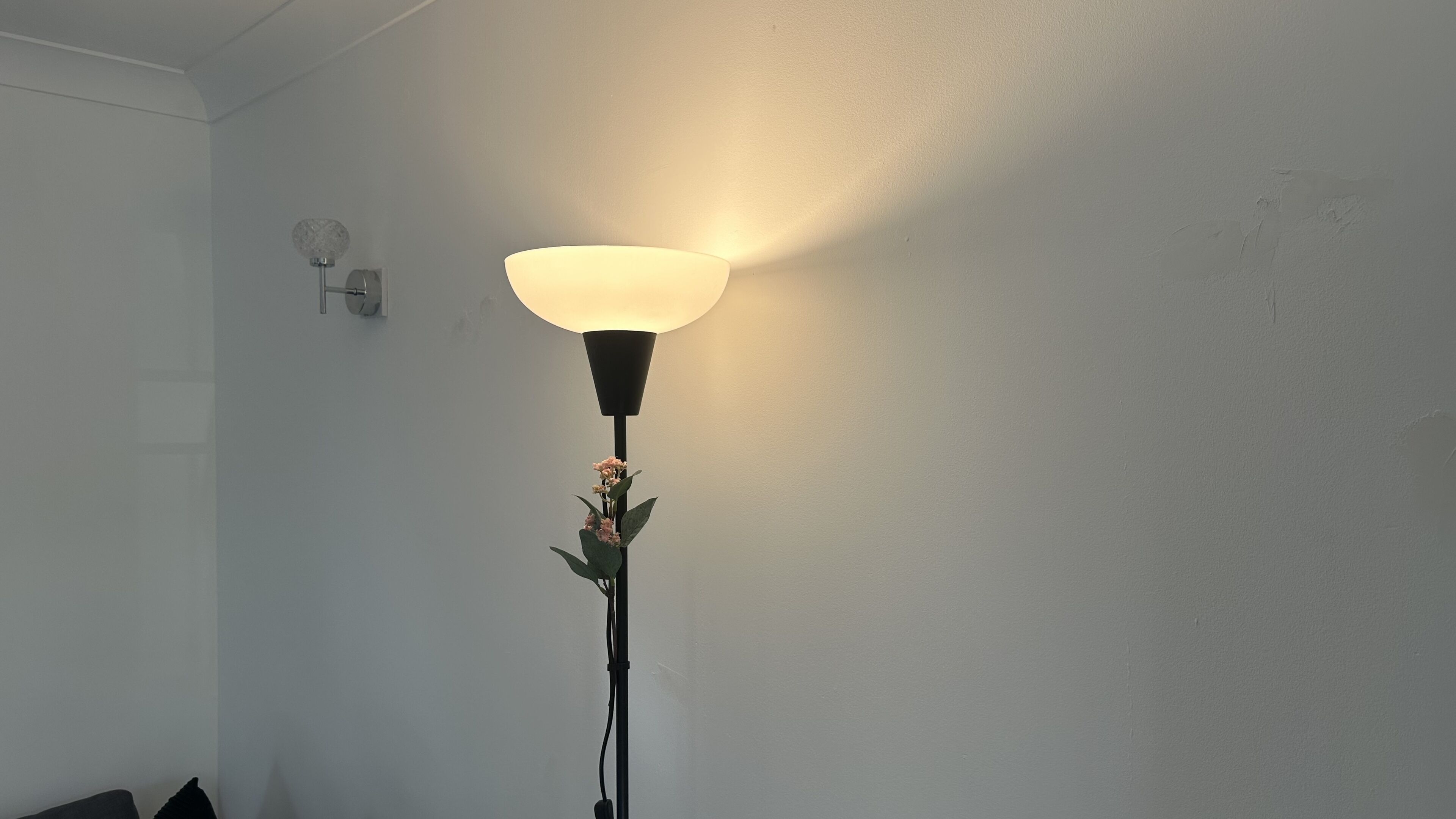 Una lámpara de pie con una pantalla grande y una planta pequeña en su base.