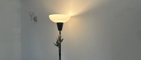 Una lámpara de pie con una pantalla grande y una planta pequeña en su base.