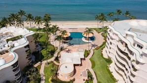 Ein Resort mit zentralem Pool, Palmen und Blick auf den Strand.