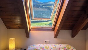Un dormitorio con tragaluces, lámpara de noche y cama con colcha de diseño colorido.