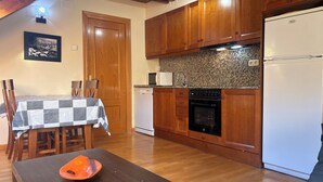 Una cocina con armarios de madera, encimera de granito, microondas, lavavajillas y refrigerador.