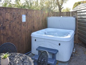Un bain à remous avec des marches, une table en métal avec des chaises, et une clôture en bois en arrière-plan.