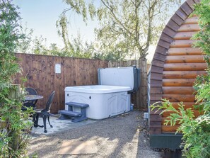 A hot tub with a wooden deck, a table, and chairs in a backyard setting. - Privet Pod - UK41394 (Lathom, near Southport)