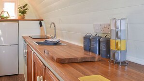 A kitchen with a wooden countertop, a sink, and stainless steel appliances. There are three stainless steel containers labeled "Coffee," "Tea," and "Sugar." - Privet Pod - UK41394 (Lathom, near Southport)