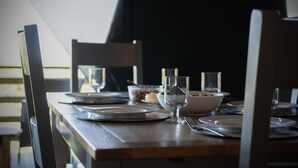 Une table à manger dressée avec des assiettes, des verres et des couverts, entourée de chaises.