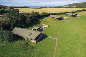 A rural property with several cabins, a large grassy field, and a view of the sea. - Burryholmes - Safari Glamping Tent - Llangennith (Llangennith)
