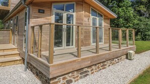 En træhytte med balkon, stensokkel og et skilt med teksten "SP2".