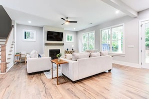 Relax in this stylish living room with a large sofa, fireplace, and expansive windows offering a view of the outdoors.
