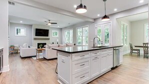 A modern kitchen with white cabinetry, a central island, and pendant lighting. - Beautiful Modern New Home Near Brookhaven Midtown (Atlanta)