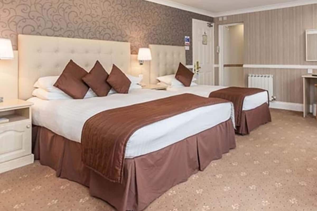 Une chambre d’hôtel avec deux lits, chacun doté d’une tête de lit, d’une table de chevet et d’une lampe.
