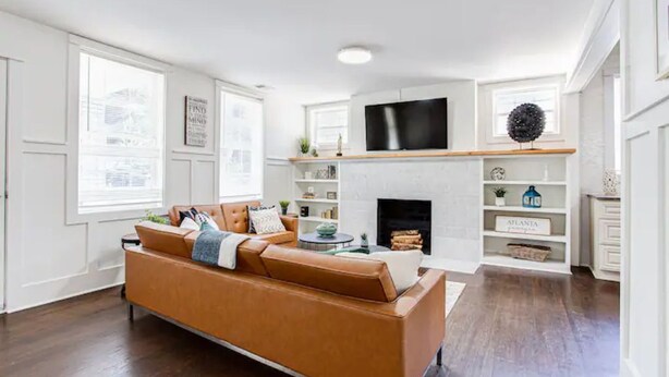 Ein modernes Wohnzimmer mit einer Ledersofa, einem Kamin und einem flachbildfernseher, der darüber angebracht ist.