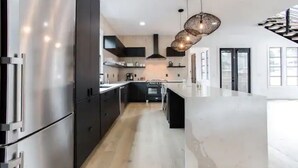 A modern kitchen with stainless steel appliances, a central island, and pendant lighting. - Sleek & Beautiful New Luxury Home In Atlanta (Atlanta)