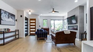 A spacious living room with a wooden floor, a blue sofa, a brown sofa, and a ceiling fan. - Sleek & Beautiful New Luxury Home In Atlanta (Atlanta)
