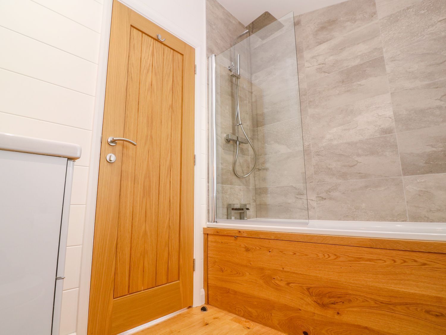 Un baño con puerta de madera, cabina de ducha de vidrio y bañera.
