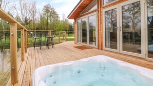 A wooden deck with a hot tub, glass doors, and outdoor furniture. - 21 Meadow Retreat (Liskeard)