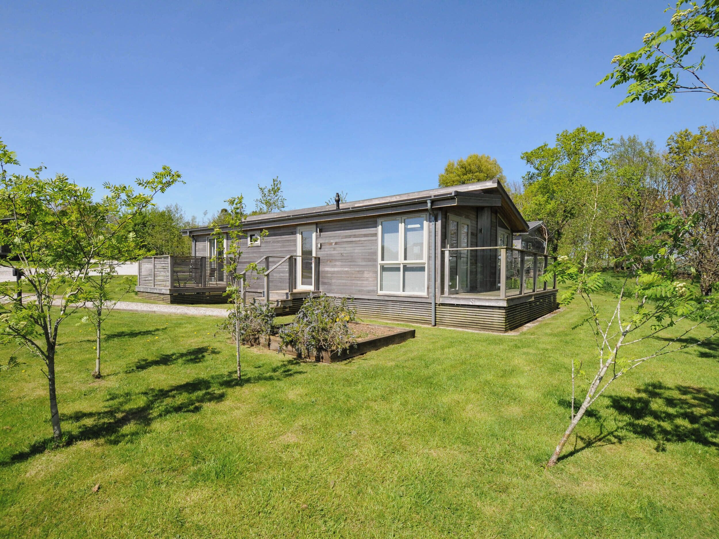 A modern, single-story house with a large deck and a small garden area.