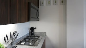 A kitchen with dark wooden cabinets, a stainless steel stove, and a knife block. - CONDO LOMA by TRVL2HM (Nuevo Nayarit)