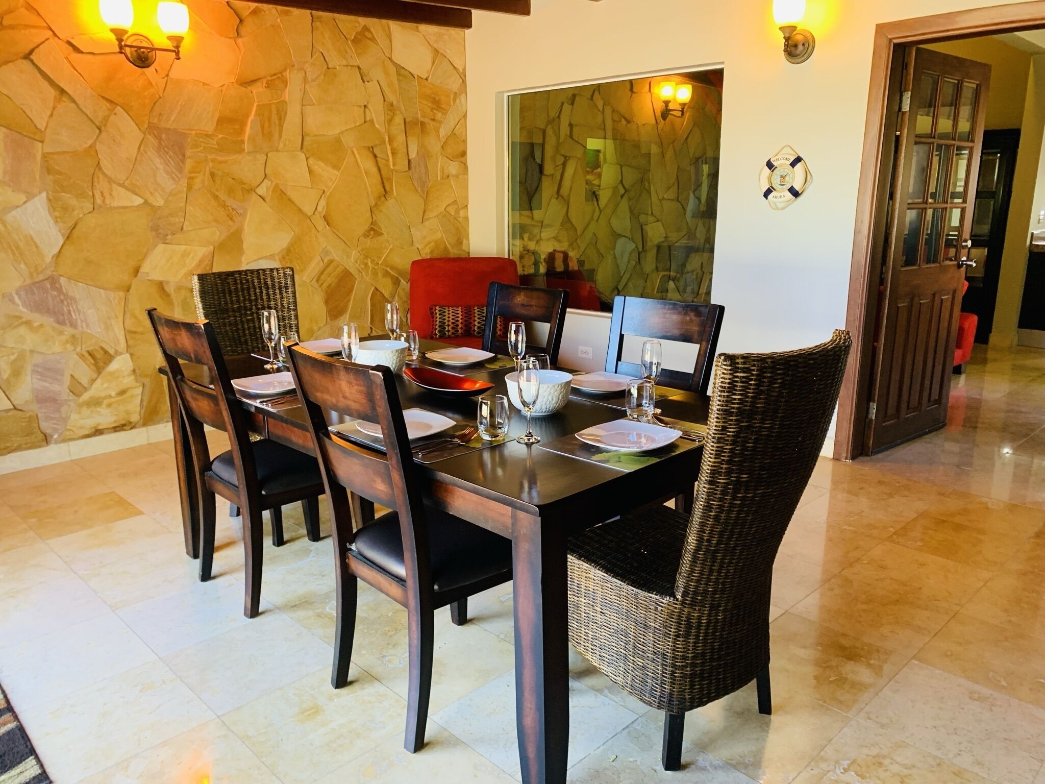 A dining area with a stone wall, a glass partition, and a wooden door.