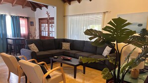 A living room with a sectional sofa, two armchairs, a coffee table, and a potted plant. - Villa Mi Dushi Cas Aruba (Noord)
