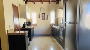 A kitchen with a central island, stainless steel appliances, and a tiled floor. - Villa Mi Dushi Cas Aruba (Noord)