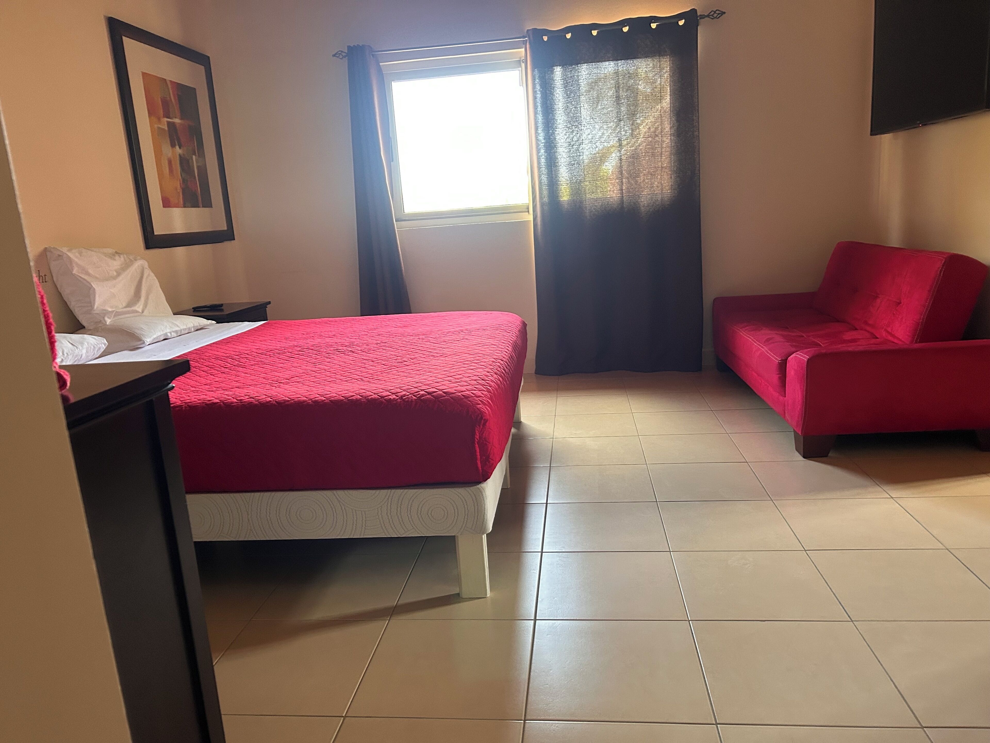 A room with a bed, a desk, a chair, and a TV on the wall.